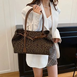 Fashionable leopard print tote bag with brown leather handles and adjustable gold buckle