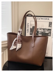 Detailaufnahme der braunen PU-Lederhandtasche mit einem dekorativen Seidenschal