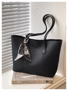 Detailaufnahme einer schwarzen PU-Ledertasche mit dekorativem Seidenschal am stabilen Griff