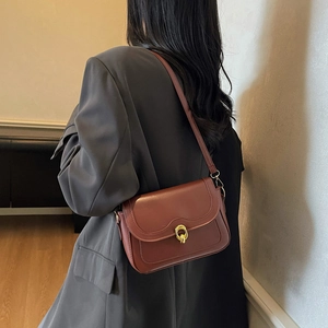 Vintage caramel leather crossbody bag with golden ring buckle on a stylish model