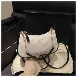 Close-up of crescent bag with golden chain in luxury gift box with silk lining