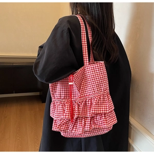 Detail of red and white plaid tote bag featuring double ruffles and drawstring closure