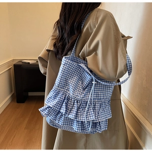 Detail of blue gingham tote bag with ruffled layers and drawstring closure on shoulder