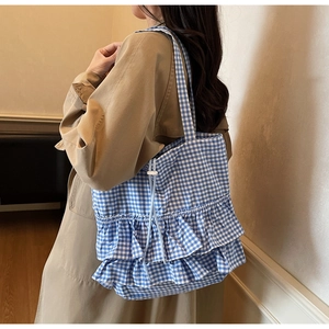 Detail of blue gingham tote bag with ruffled edges and drawstring closure on shoulder