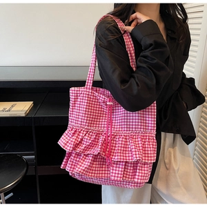 Close-up of pink gingham tote bag with ruffle layers and drawstring detail on model