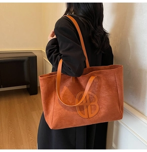 Detailed back view of a large vintage orange suede tote bag with geometric embossed logo
