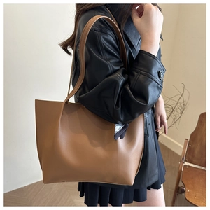 Close-up of brown minimalist tote bag with decorative silk scarf on leather strap