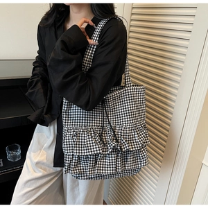 Close-up of black and white plaid tote bag featuring decorative ruffle pleated details