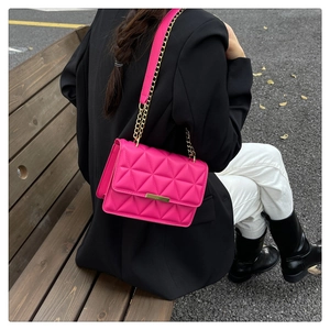 Piccola borsa trapuntata rosa con catena dorata indossata da una modella all'aperto