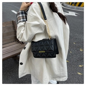 Close-up of quilted black PU leather texture and gold chain strap on the handbag