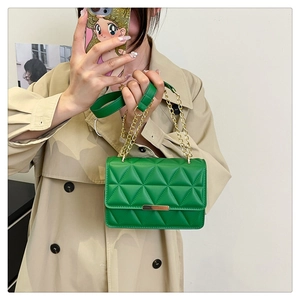 Detail of green quilted handbag with gold chain strap and metallic bar closure