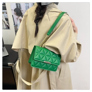 Close-up of green quilted bag with gold hardware worn with a beige trench coat