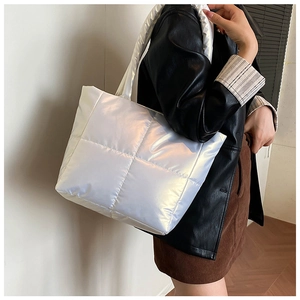 Close-up of pearl white quilted tote bag with a glossy finish on a shoulder model