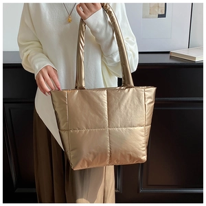 Detail of champagne gold puffer tote bag with quilted pattern and metallic finish
