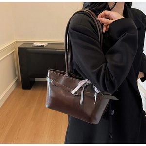Dettaglio borsa tote lucida marrone scuro con fibbia a cintura e foulard di seta a scacchi