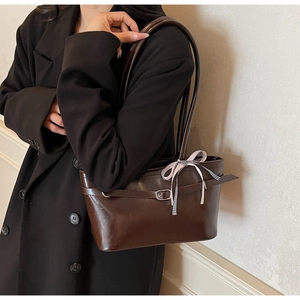 Dettaglio della borsa tote in pelle marrone scuro con fibbia in metallo e nastro rosa