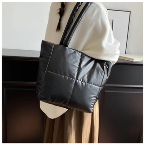 Close-up of black quilted puffer tote bag with large square stitching and padded straps
