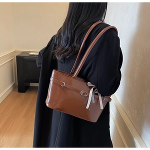 Dettaglio della borsa tote in pelle marrone con nastro a quadretti e fibbia in metallo