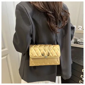 Detail of gold quilted chain bag with metallic finish worn with a grey suit blazer