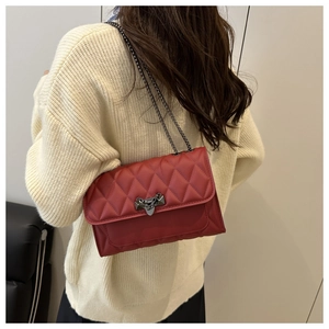 Detailed view of a red quilted leather crossbody bag with metallic chain and buckle
