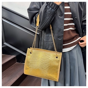 Détail du sac cabas doré avec motif crocodile et bandoulières en chaîne métallique
