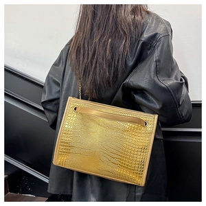 Détail de la texture croco dorée et de la chaîne métallique sur un sac à main chic