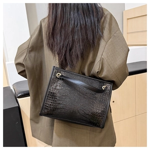 Détail du sac cabas à motif crocodile avec chaîne dorée porté par un mannequin