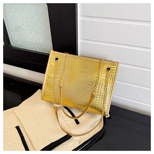 Vue détaillée de la texture crocodile dorée et des poignées en chaîne de ce sac fourre-tout