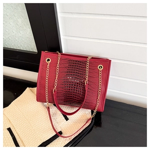 Gros plan sur la texture crocodile rouge et les détails de la chaîne dorée du sac