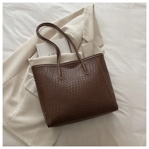 Détail d'un grand cabas marron à texture tressée dans un décor de style minimaliste