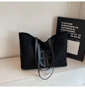 Close-up of large suede tote bag with geometric circular patch and slim leather straps