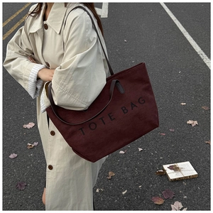 Detail view of large burgundy canvas tote bag with shoulder strap and letter print