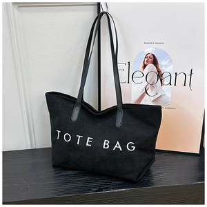 Detailansicht einer schwarzen Shopper-Tasche mit weißem Schriftzug und Lederriemen