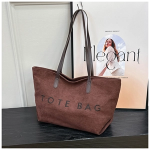 Detail einer braunen Wildleder-Tragetasche mit TOTE BAG Aufdruck auf dunklem Untergrund