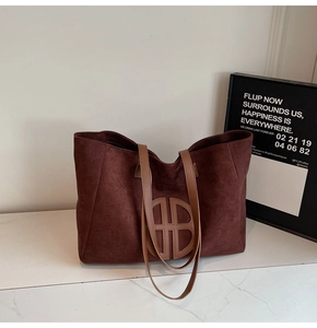 Detail of suede tote bag showing dark brown matte texture and circular leather logo