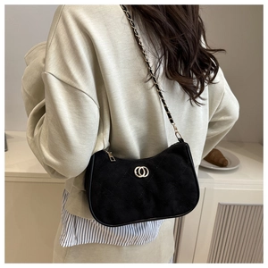 Rear view of a model wearing a black quilted faux suede shoulder bag with gold chain strap