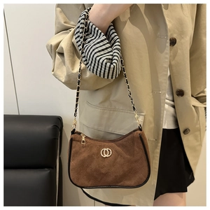 Close-up of brown quilted suede shoulder bag with gold chain and circular buckle detail