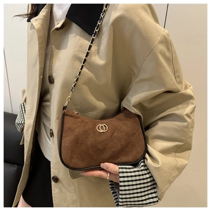 Detail of dark brown suede shoulder bag featuring quilted stitching and gold chain strap