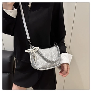 Détail du sac bandoulière argenté plissé avec chaîne et pendentif nœud en perles