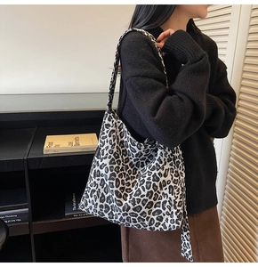 Detail of a large leopard print canvas tote bag with fashion label shown in a lifestyle shot