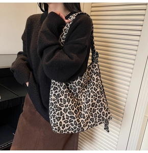 Close-up of leopard print canvas tote bag with wide strap on model in cozy indoor setting