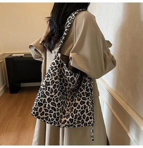 Detailed side view of large leopard print canvas tote bag with woven fashion label