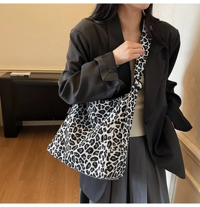 Detail of the leopard print canvas crossbody bag featuring a wide strap and fashion label