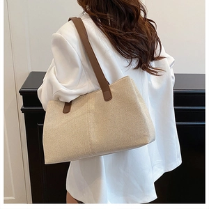 Close-up of cream canvas tote bag with brown leather handles showing woven texture details