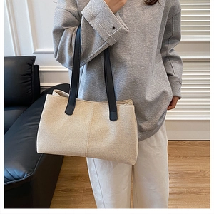 Close-up of cream canvas tote bag showing weave texture and black leather shoulder straps