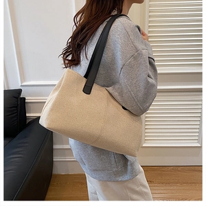 Close-up of a large beige canvas tote bag with black leather handles for daily commute
