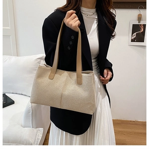 Detail of canvas tote bag with brown leather handles worn over the shoulder