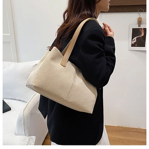 Side view of a large beige woven tote bag with brown leather straps on a model