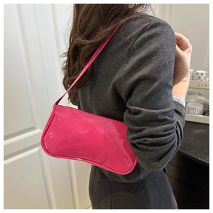 Side view of a glossy hot pink baguette shoulder bag in patent leather on a model