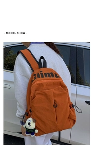Mochila naranja resistente al agua con colgante de peluche en modelo en entorno exterior
